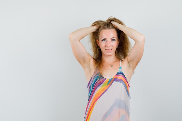 Young lady holding hands in hair in summer dress and looking elegant. 