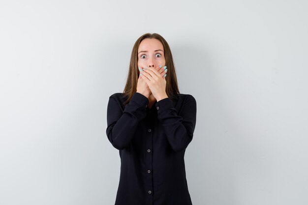 Young lady holding hands on mouth and looking frightened