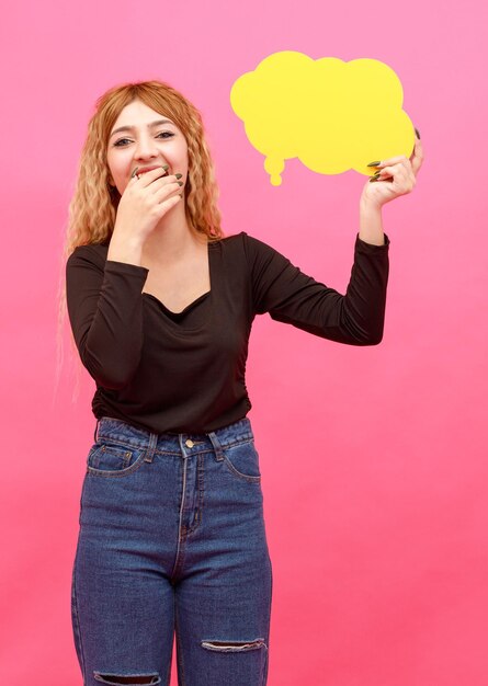 Young lady holding idea board and laughing on pink background