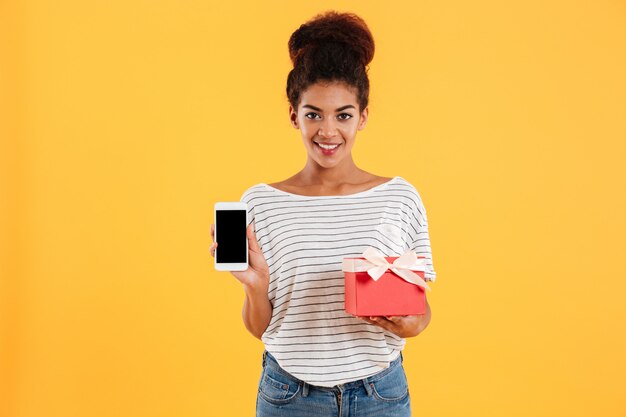 空白の画面と現在の携帯電話を保持している若い女性