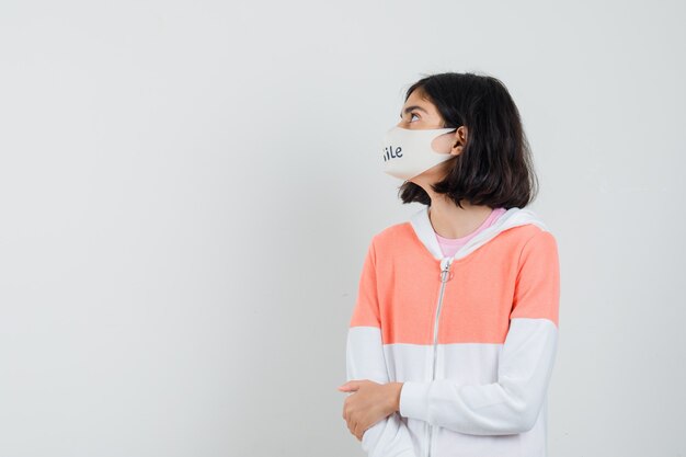 Young lady in hoodie, face mask looking aside .