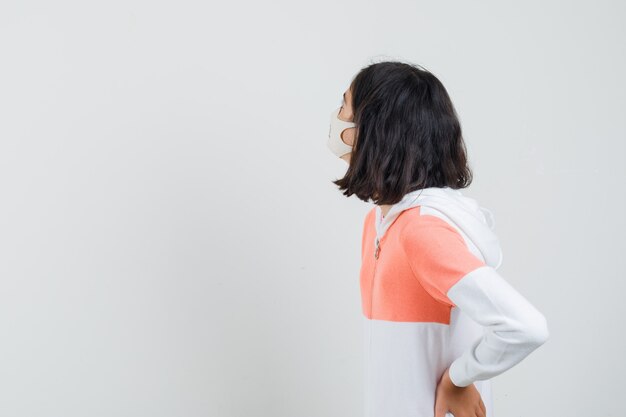 Young lady in hoodie, face mask looking back and looking interested .