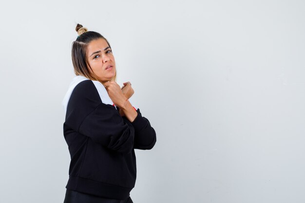 Young lady in hoodie sweater holding crossed arms on chest and looking attractive