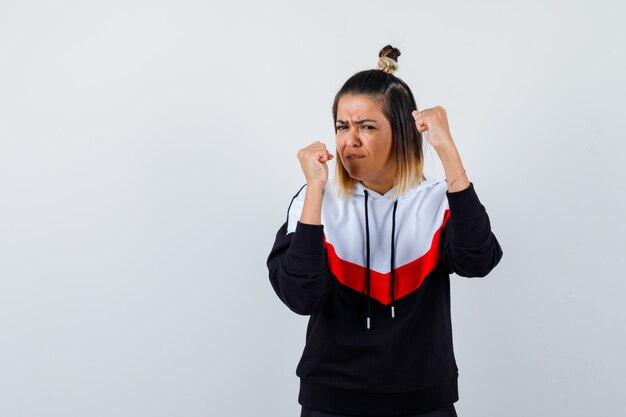 Young lady in hoodie sweater standing in fight pose and looking self-confident