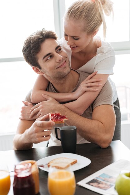 Young lady hug her man while they have breakfast