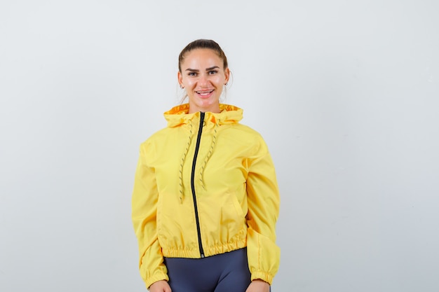 Бесплатное фото Девушка в желтой куртке позирует и выглядит радостным, вид спереди.