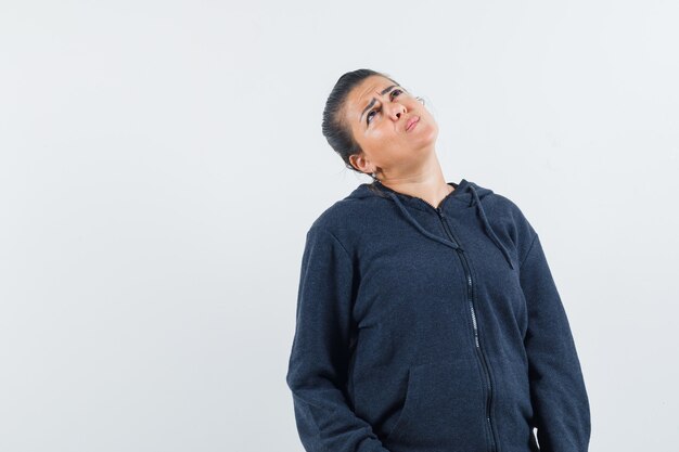 Young lady in jacket looking up and looking thoughtful 