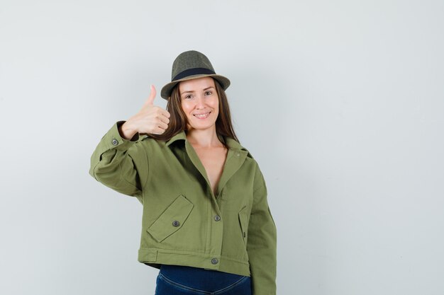 Free photo young lady in jacket pants hat showing thumb up and looking cheery