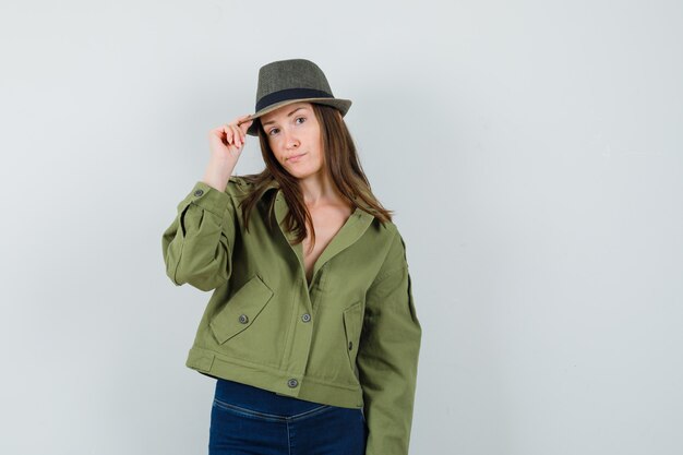 Young lady in jacket pants holding her hat and looking elegant  