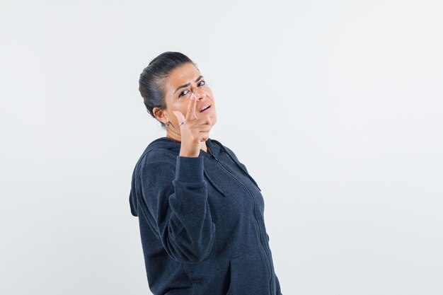 Young lady in jacket pointing at camera 