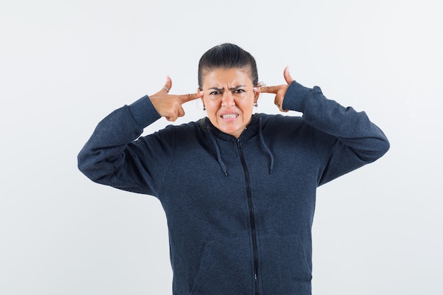 Young lady in jacket pointing to her head and looking aggressive 