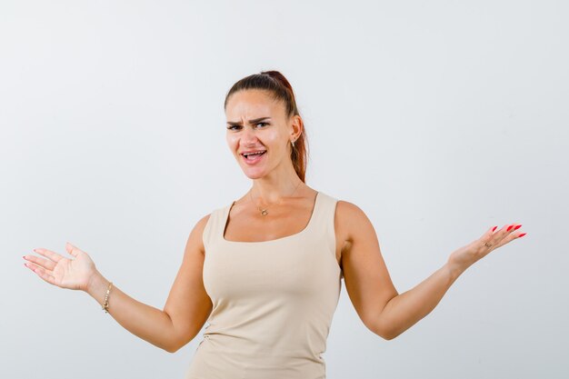 Young lady keeping arms wide spread in tank top and looking confident , front view.