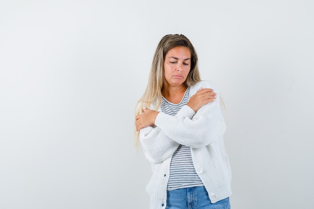 Young lady keeping crossed arms on chest in t-shirt, jacket, jeans and looking depressed. front view.