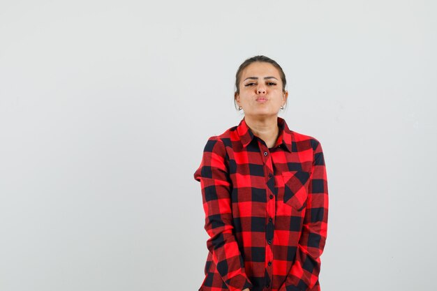 Young lady keeping lips folded in checked shirt and looking tempting