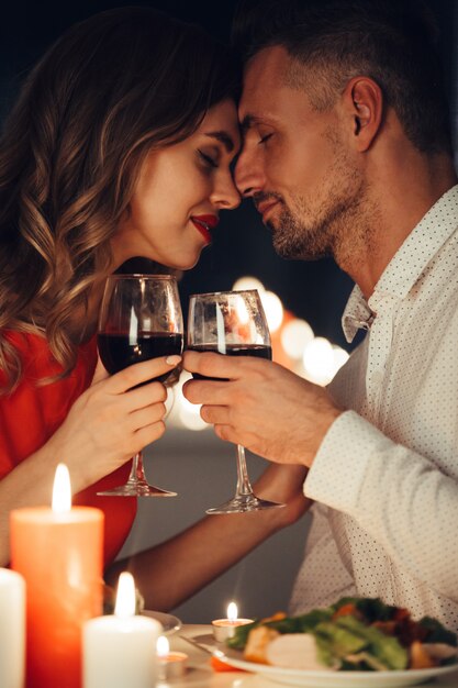 Барышня целует своего шикарного мужчину во время романтического ужина