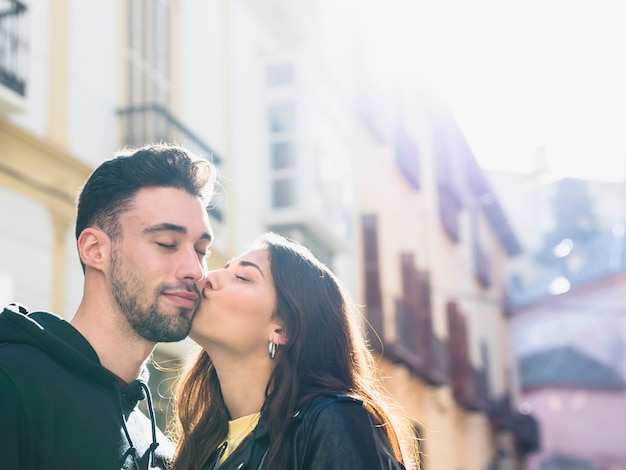 Young lady kissing positive guy on street