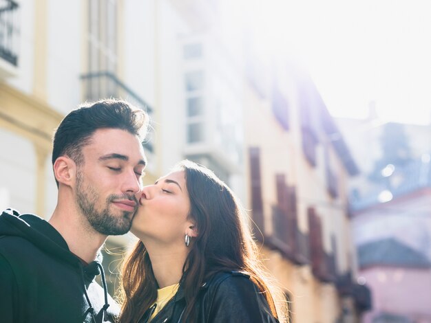 Young lady kissing positive guy on street