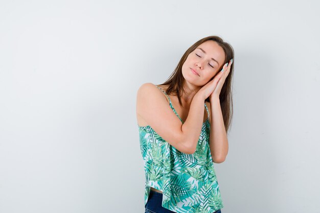 Young lady leaning on palms as pillow and looking sleepy. front view.