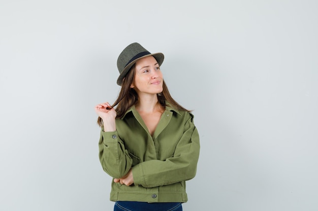 Young lady looking aside in jacket pants hat and looking peaceful 