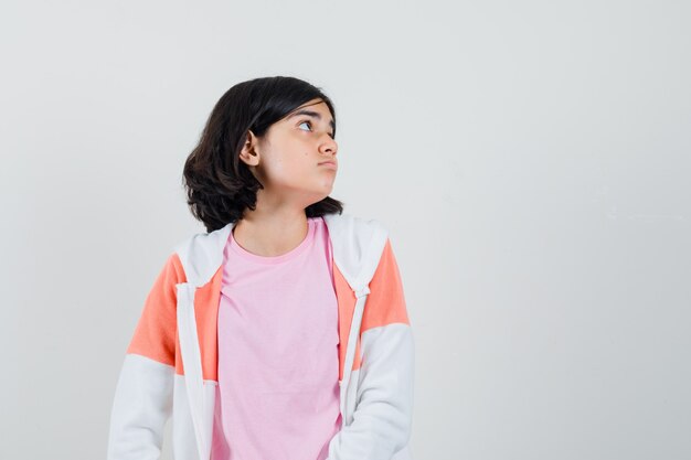 Young lady looking aside in jacket, pink shirt and looking upset