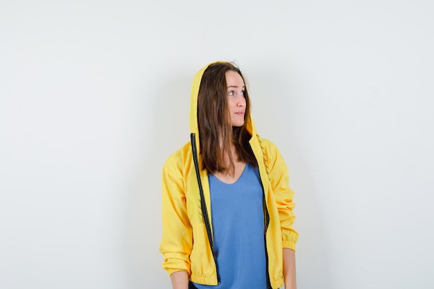 Young lady looking aside in t-shirt, jacket and looking hopeful