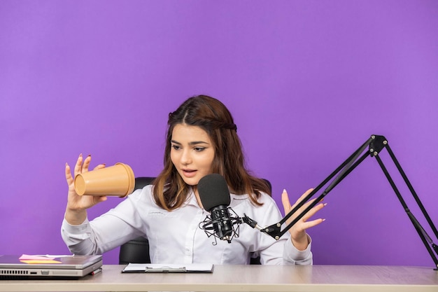 彼女の空のコーヒーマグを見ている若い女性高品質の写真