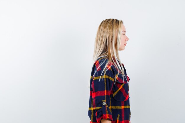 Young lady looking away in checked shirt and looking confident. front view.