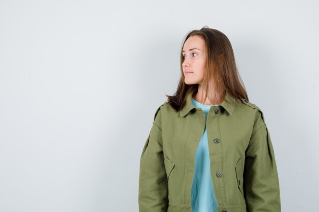 Молодая леди, глядя в футболку, куртку и задумчиво, вид спереди.
