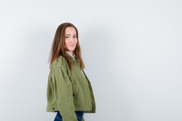 Young lady looking at camera over her shoulder in shirt, jacket and looking charming.