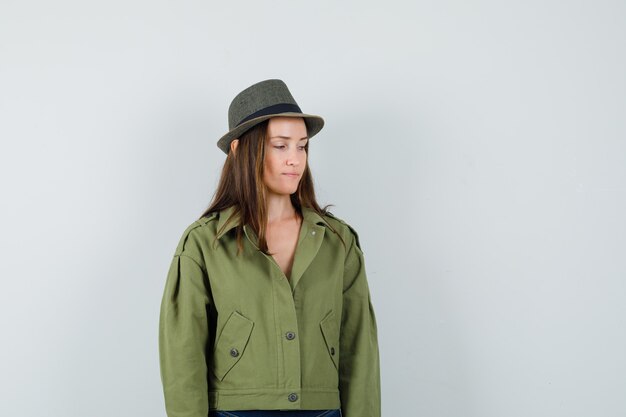 Young lady looking down in jacket pants hat and looking pensive 