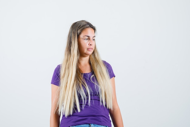 Young lady looking down in violet t-shirt and looking pensive , front view.