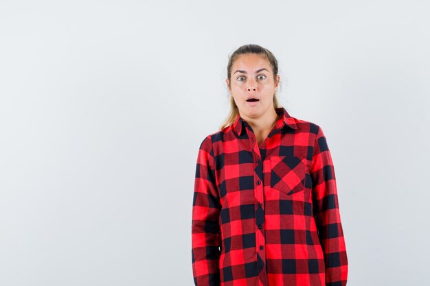 Young lady looking at front in checked shirt and looking astonished