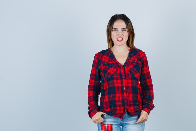 Young lady looking at front in checked shirt and looking nervous. front view.