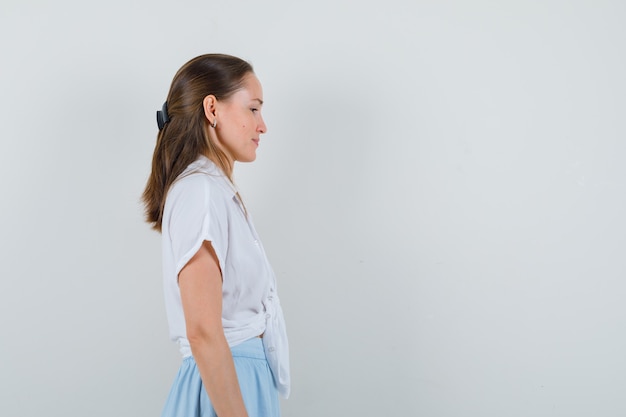 Young lady looking at the front of her in blouse and skirt and looking focused. .