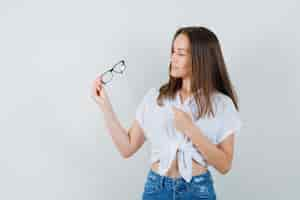 Free photo young lady looking at her glasses in white blouse front view.