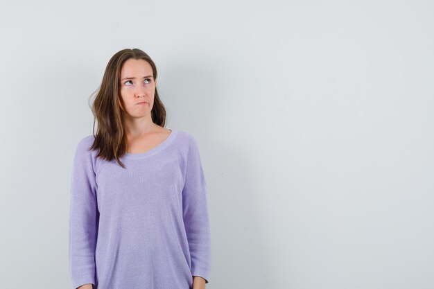 Young lady looking up in casual shirt and looking pensive. front view.