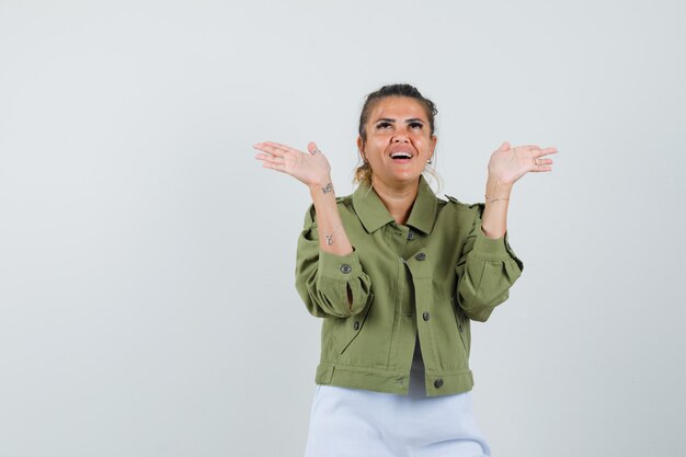 Tシャツジャケットで開いた手のひらを上げて幸せそうに見える若い女性