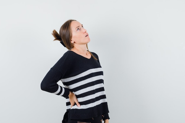 Foto gratuita giovane donna che guarda verso l'alto in camicia casual e sembra annoiata