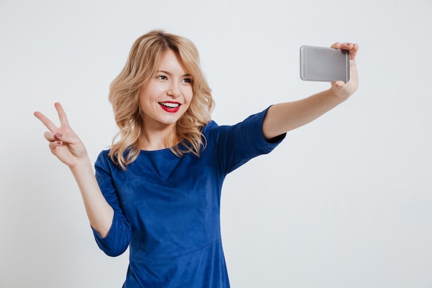 Young lady make selfie with peace gesture by phone