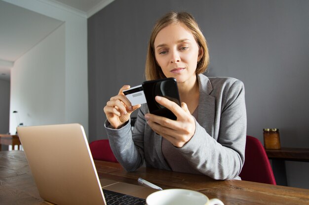 Молодая леди, делая онлайн-платежей с помощью смартфона