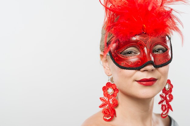 Young lady in mask with red feathers and earrings 