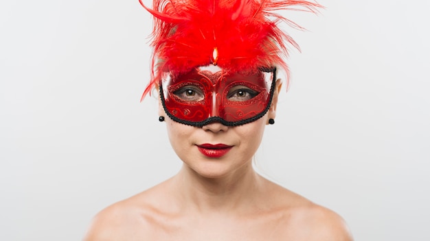 赤い羽毛のマスクの若い女性