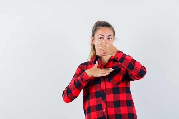 Young lady pinching nose due to bad smell in checked shirt and looking disgusted