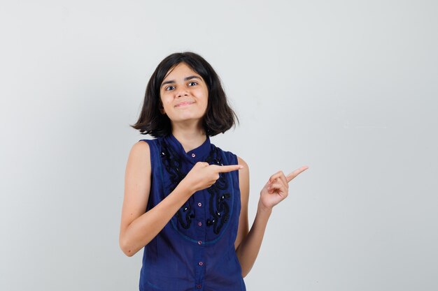 Young lady pointing aside in blouse and looking pleased