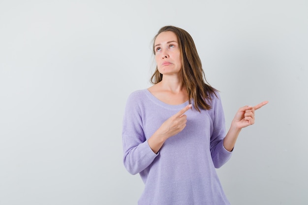 Young lady pointing aside in casual shirt and looking arrogant 