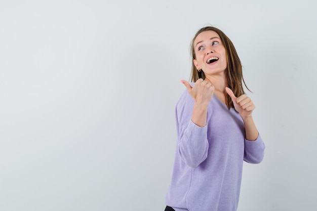 Young lady pointing aside in casual shirt and looking glad 