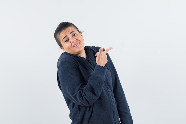 Young lady pointing aside in jacket 