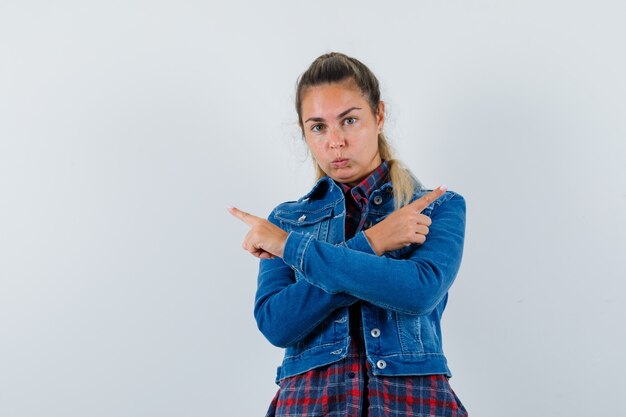 Young lady pointing away in shirt, jacket and looking serious , front view.