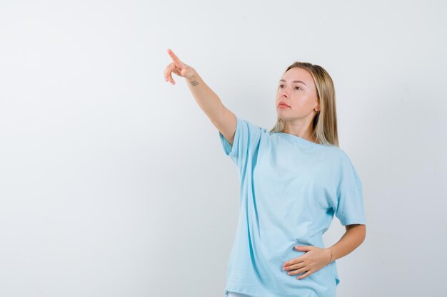 Young lady pointing away in t-shirt and looking confident isolated