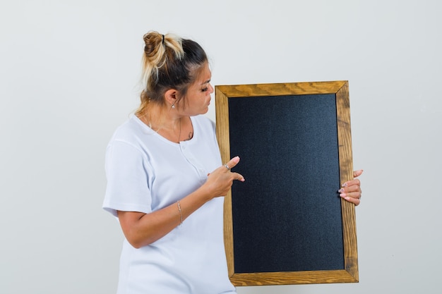 Young lady pointing at blackboard in t-shirt 